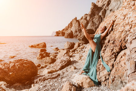 Side view a Young beautiful sensual woman with black hair in a long mint dress posing on a beach with calm sea bokeh lights on sunny day. Girl on the nature on blue sky background. Fashion photoの写真素材