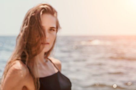 Woman summer travel sea. Happy tourist in hat enjoy taking picture outdoors for memories. Woman traveler posing on the beach at sea surrounded by volcanic mountains, sharing travel adventure journeyの写真素材