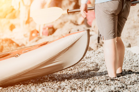 Happy couple kayaks in an inflatable kayak on the sea at sunset. Couple kanoeing in the sea near the island with mountains. People kayaking in life jackets sail. Back viewの写真素材