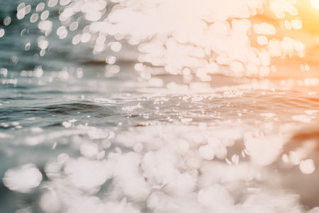 Abstract sea summer ocean sunset nature background. Small waves on golden water surface in motion blur with golden bokeh lights from sun. Holiday, vacation and recreational concept.の写真素材