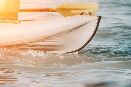 Happy couple kayaks in an inflatable kayak on the sea at sunset. Couple kanoeing in the sea near the island with mountains. People kayaking in life jackets sail. Back viewの写真素材