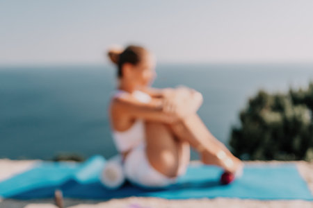 Abstract defocused fitness woman sea. A happy middle aged woman in white sportswear exercises morning outdoors in a park with a beach view. Female fitness pilates yoga routine concept. Healthy lifestyle.の写真素材