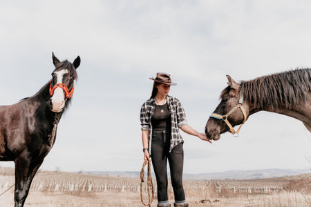 Young happy woman in hat with her horse in evening sunset light. Outdoor photography with fashion model girl. Lifestyle mood. Concept of outdoor riding, sports and recreation.の写真素材