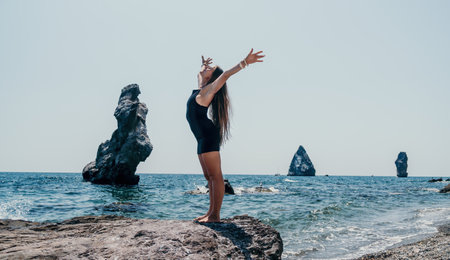 Woman summer travel sea. Happy tourist in hat enjoy taking picture outdoors for memories. Woman traveler posing on the beach at sea surrounded by volcanic mountains, sharing travel adventure journeyの写真素材