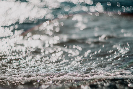 Blurred golden sea at sunset. The sun reflects and sparkles on the waves with bokeh, illuminating the golden sea. Holiday recreation concept. Abstract nautical summer ocean sunset nature background.の写真素材