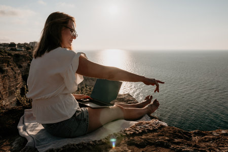 Woman sea laptop. Business woman working on laptop by sea at sunset. Close up on hands of pretty lady typing on computer outdoors summer day. Freelance, digital nomad, travel and holidays concept.の写真素材