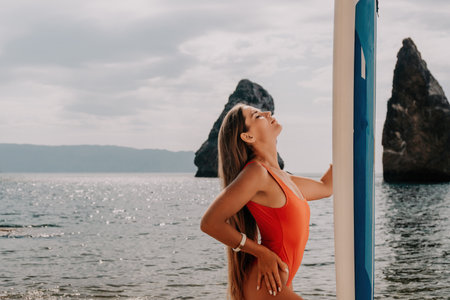 Woman sea sup. Close up portrait of happy young caucasian woman with long hair looking at camera and smiling. Cute woman portrait in bikini posing on sup board in the seaの写真素材
