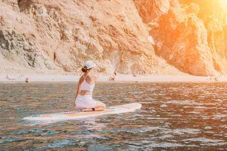 Woman sup yoga. Happy sporty woman practising yoga pilates on paddle sup surfboard. Female stretching doing workout on sea water. Modern individual female hipster outdoor summer sport activity.の写真素材