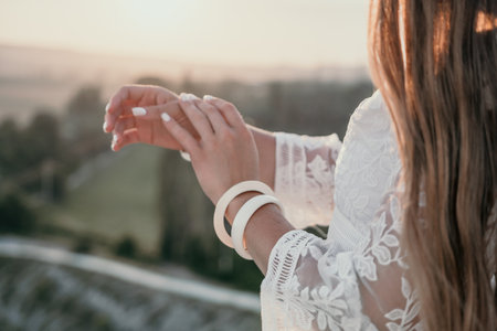 Happy woman in white boho dress on sunset in mountains. Romantic woman with long hair standing with her back on the sunset in nature in summer with open hands. Silhouette. Nature. Sunset.の写真素材