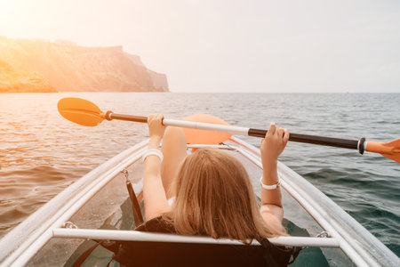 Woman in kayak back view. Happy young woman with long hair floating in transparent kayak on the...