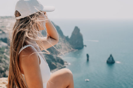 Woman summer travel sea. Happy tourist enjoy taking picture outdoors for memories. Woman traveler posing over sea bay surrounded by volcanic mountains, sharing travel adventure journeyの写真素材