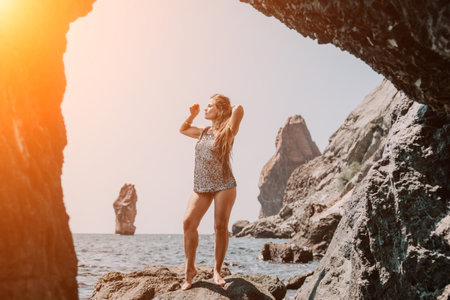 Woman summer travel sea. Happy tourist enjoy taking picture outdoors for memories. Woman traveler posing on the beach at sea surrounded by volcanic mountains, sharing travel adventure journeyの写真素材
