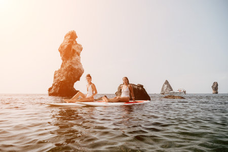 Woman sup yoga. Happy sporty woman practising yoga pilates on paddle sup surfboard. Female stretching doing workout on sea water. Modern individual female hipster outdoor summer sport activity.の写真素材