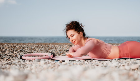 Woman sea pilates. Sporty happy middle aged woman practicing fitness on beach near sea, smiling...