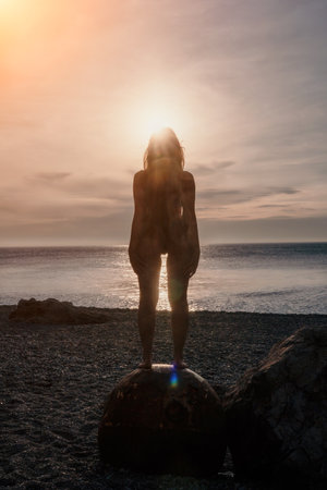 Woman summer travel sea. A happy tourist enjoys taking pictures of her travels, posing by an old, rusty sea mine on a beach surrounded by volcanic mountains, sharing travel adventure journeyの写真素材