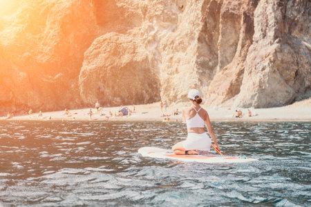 Woman sup yoga. Happy sporty woman practising yoga pilates on paddle sup surfboard. Female stretching doing workout on sea water. Modern individual female hipster outdoor summer sport activity.の写真素材