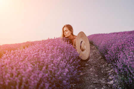 Woman lavender field. Happy carefree woman in beige dress and hat with large brim smelling a blooming lavender on sunset. Perfect for inspirational and warm concepts in travel and wanderlust. Close upの写真素材