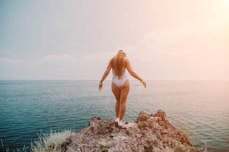 Woman travel sea. Happy tourist in hat enjoy taking picture outdoors for memories. Woman traveler posing on the beach at sea surrounded by volcanic mountains, sharing travel adventure journeyの写真素材