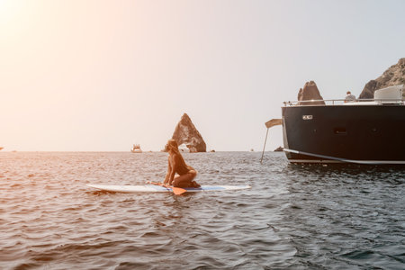 Woman sea sup. Close up portrait of happy young caucasian woman with long hair looking at camera and smiling. Cute woman portrait in bikini posing on sup board in the seaの写真素材