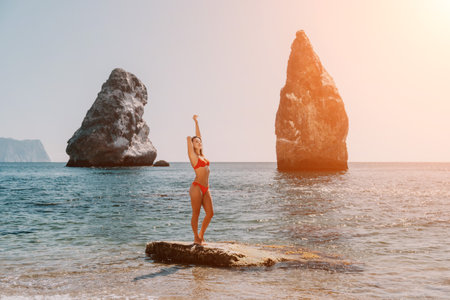 Woman summer travel sea. Happy tourist enjoy taking picture outdoors for memories. Woman traveler posing on the beach at sea surrounded by volcanic mountains, sharing travel adventure journeyの写真素材