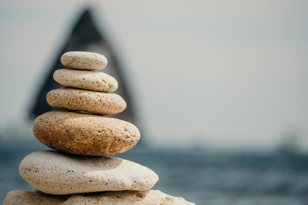 balanced rock pyramid on the pebbled beach is a study in harmony and balance. golden sea bokeh provide a stunning backdrop at sunset. Zen stones invite meditation and calm. spa or wellness concept.の写真素材