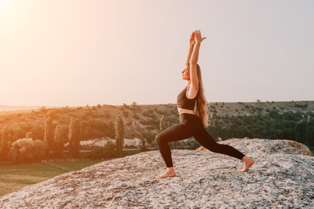Fitness woman. Happy middle-aged fitness woman doing stretching and pilates on a rock near forest at sunset. Female fitness yoga routine. Healthy lifestyle with focus on well-being and relaxation.の写真素材