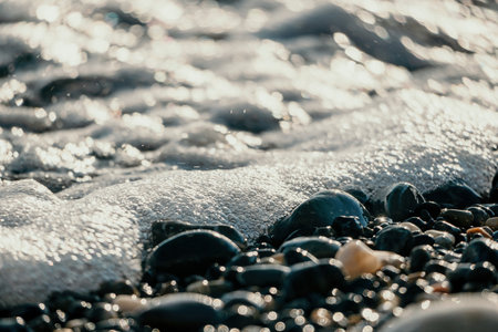 Blurred golden sea at sunset. The sun reflects and sparkles on the waves with bokeh, illuminating the golden sea. Holiday recreation concept. Abstract nautical summer ocean sunset nature background.の写真素材