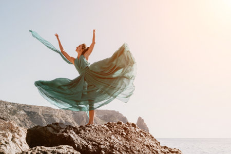 Side view a Young beautiful sensual woman with black hair in a long mint dress posing on a beach with calm sea bokeh lights on sunny day. Girl on the nature on blue sky background. Fashion photoの写真素材