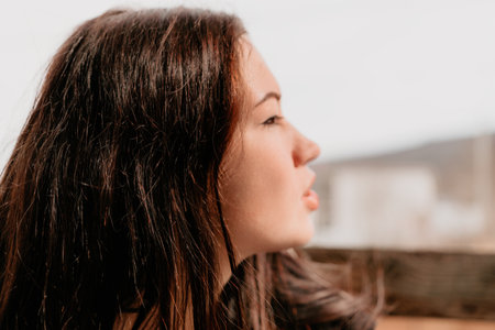 Happy young smiling woman with freckles outdoors portrait. Soft sunny colors. Outdoor close-up portrait of a young brunette woman and looking to the camera, posing against autumn nature backgroundの写真素材