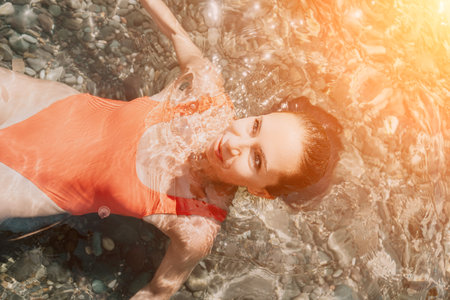 Woman travel portrait. Close-up portrait of a happy woman with long hair in a red bikini, floating...