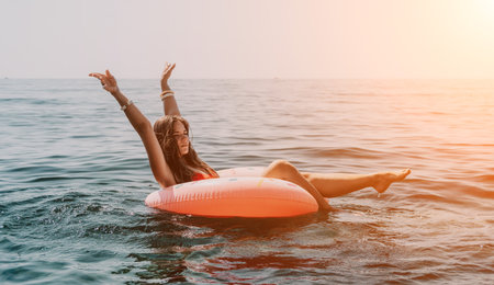 Woman summer sea. Happy woman swimming with inflatable donut on the beach in summer sunny day,...