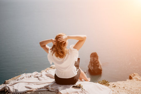 Woman sea laptop. Successful business woman working on laptop by the sea. Pretty lady typing on computer at summer day outdoors. Freelance, digital nomad, travel and holidays concept.の写真素材
