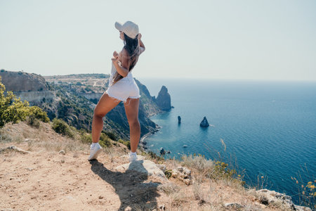 Woman summer travel sea. Happy tourist enjoy taking picture outdoors for memories. Woman traveler posing over sea bay surrounded by volcanic mountains, sharing travel adventure journeyの写真素材