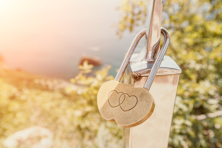 Wedding Heart Golden Lock on stainless iron fence. Valentines day. Symbol of eternal love. A wedding tradition all over the world to hinder the lock. Monument on the wedding day.の写真素材