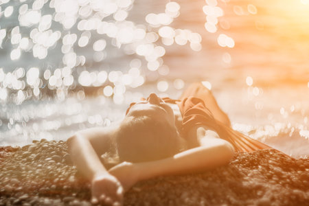 Woman in red dress on sea. Side view a Young beautiful sensual woman in a red long dress posing on the beach near sea on sunset. Girl on the nature on blue sky background. Fashion photo.の写真素材