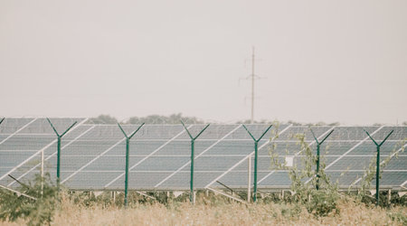 Large solar station with blue photovoltaic panels fenced with lattice and barbed wire. Producing clean energy from the sun and minimizing the carbon footprint.の写真素材