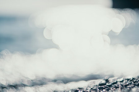 Abstract nature summer ocean sunset sea background. Small waves on water surface in motion blur with bokeh lights from sunrise. Holiday, vacation and recreational background concept.の写真素材