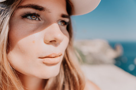 Woman travel portrait. Happy woman with long hair looking at camera and smiling. Close up portrait cute woman in a mint long dress posing on a volcanic rock high above the seaの写真素材