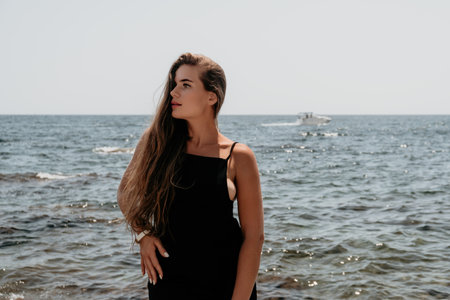 Woman summer travel sea. Happy tourist in hat enjoy taking picture outdoors for memories. Woman traveler posing on the beach at sea surrounded by volcanic mountains, sharing travel adventure journeyの写真素材