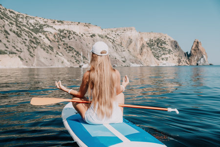 Woman sea sup. Close up portrait of happy young caucasian woman with long hair looking at camera and smiling. Cute woman portrait in bikini posing on sup board in the seaの写真素材