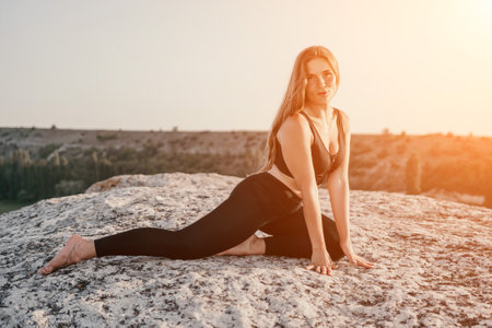 Fitness woman. Happy middle-aged fitness woman doing stretching and pilates on a rock near forest at sunset. Female fitness yoga routine. Healthy lifestyle with focus on well-being and relaxation.の写真素材