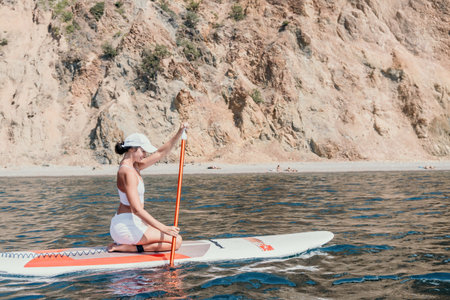 Woman sup yoga. Happy sporty woman practising yoga pilates on paddle sup surfboard. Female...