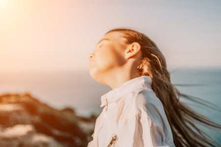 Adorable teenage girl outdoors enjoying sunset at beach on summer day. Close up portrait of smiling young romantic teenager girl with long hair on beach at summer evening. Travel and holidaysの写真素材