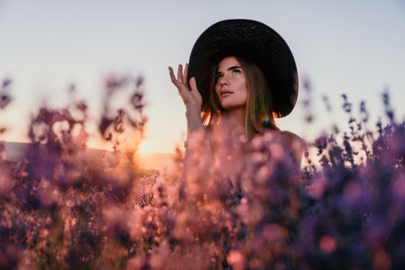 Woman lavender field. Happy carefree woman in black dress and hat with large brim walking in a lavender field during sunset. Perfect for inspirational and warm concepts in travel and wanderlust.の写真素材