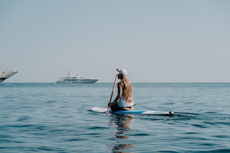 Woman sea sup. Close up portrait of happy young caucasian woman with long hair looking at camera and smiling. Cute woman portrait in bikini posing on sup board in the seaの写真素材