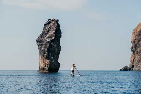 Woman sea sup. Close up portrait of happy young caucasian woman with long hair looking at camera and smiling. Cute woman portrait in bikini posing on sup board in the seaの写真素材