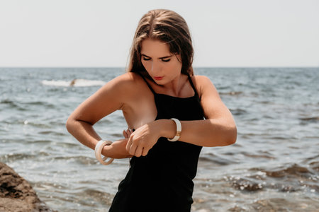 Woman summer travel sea. Happy tourist in hat enjoy taking picture outdoors for memories. Woman traveler posing on the beach at sea surrounded by volcanic mountains, sharing travel adventure journeyの写真素材