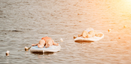 Woman sup yoga. Happy sporty woman practising yoga pilates on paddle sup surfboard. Female...