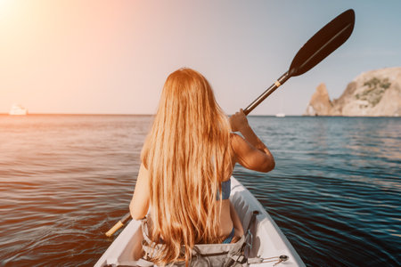 Woman in kayak back view. Happy young woman with long hair floating in kayak on calm sea. Summer holiday vacation and cheerful female people relaxing having fun on the boat.の写真素材