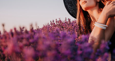 Woman lavender field. Happy carefree woman in black dress and hat with large brim smelling a blooming lavender on sunset. Perfect for inspirational and warm concepts in travel and wanderlust. Close upの写真素材